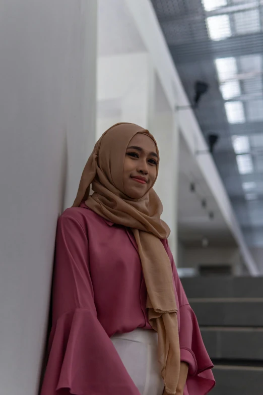 a young woman stands next to a wall