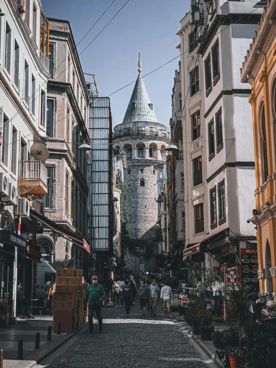 the view of a narrow street with people walking on it