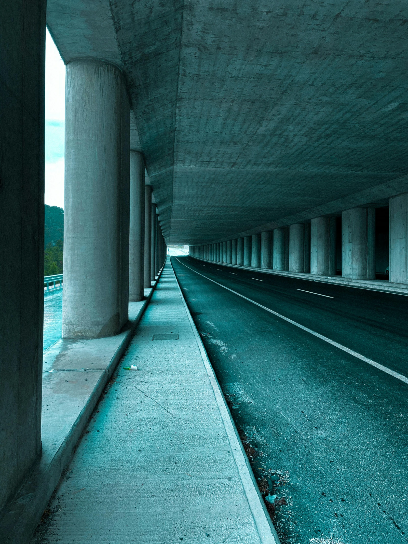 a long road under an overpass with tall pillars