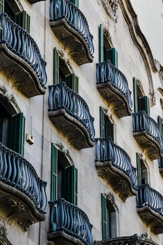 many balconies on one wall next to a building with green shutters