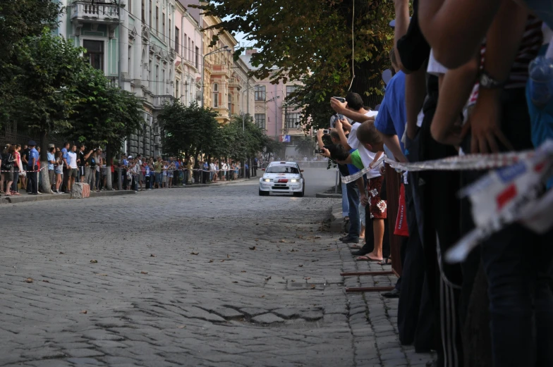 a line of people watch as a rally passes by