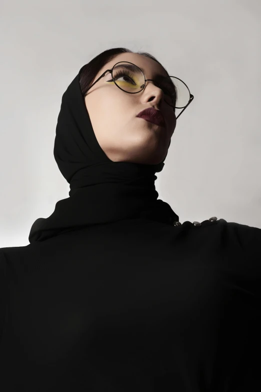 woman in black coat and yellow glasses poses