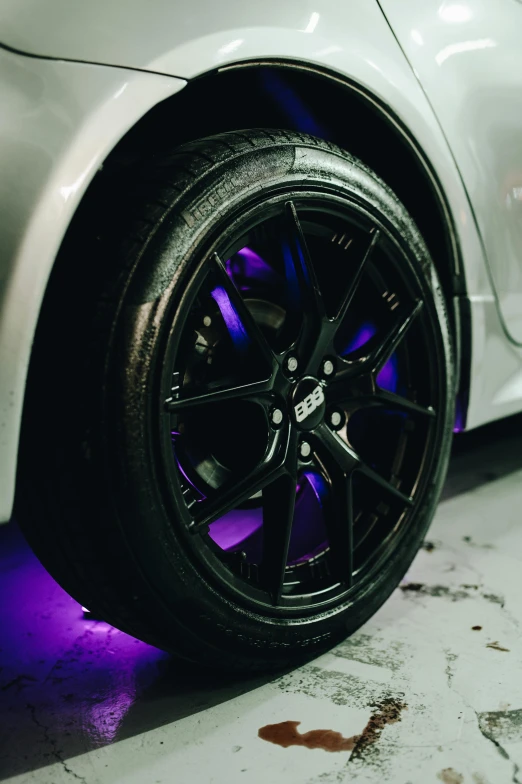 the front tire of a white sports car with a purple light on it
