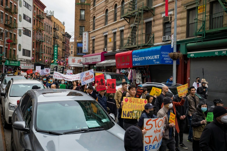 a crowd of people standing on a sidewalk holding signs