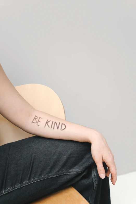 a person with a tattoo reading be kind