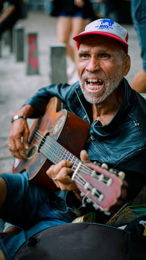 an old man playing the ukelers while holding another guitar
