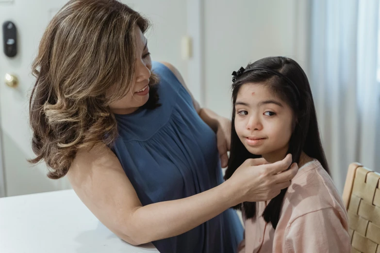 woman putting on her hair while another woman sits beside her