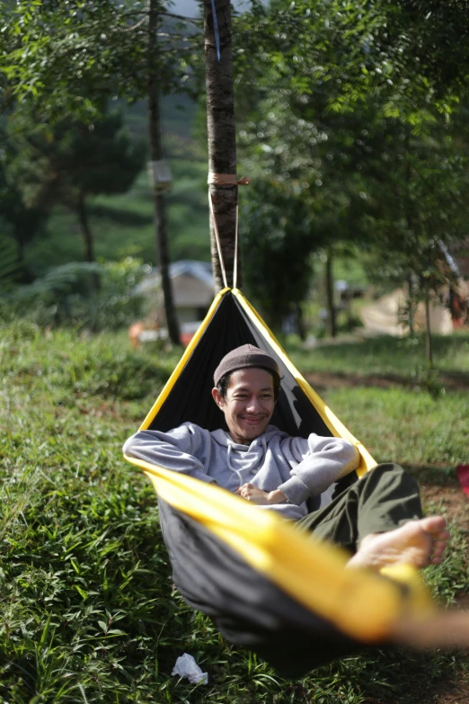 a smiling man lying in a hammock chair