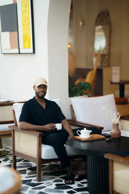 a black man is sitting down with a cup