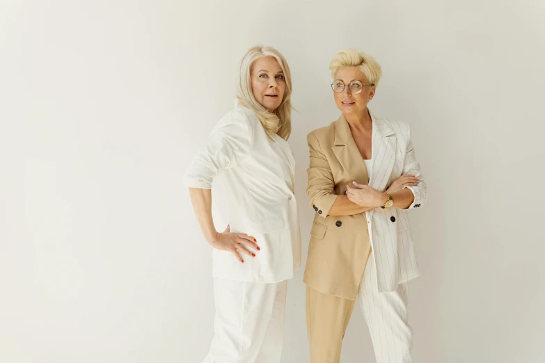 two older women in white standing side by side