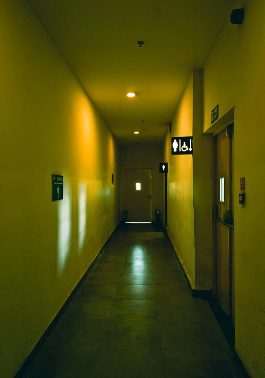 a narrow corridor with some exit lights on