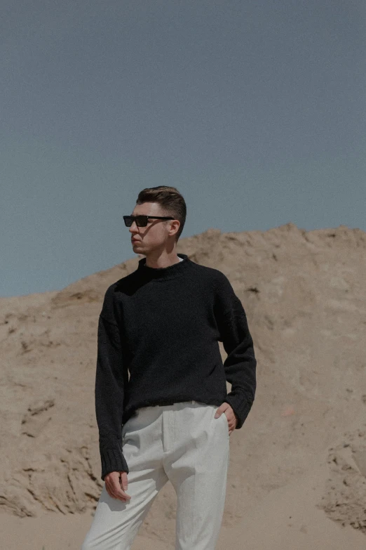 a man in sunglasses standing next to a rock wall