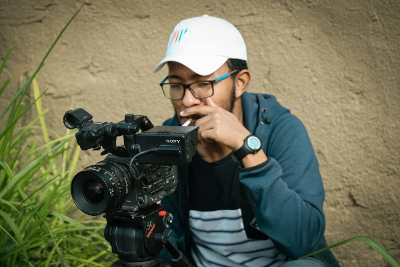 man in cap is using video camera near plants