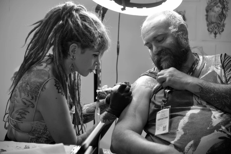 a man holding a woman's arm while she is working on the arm of the man