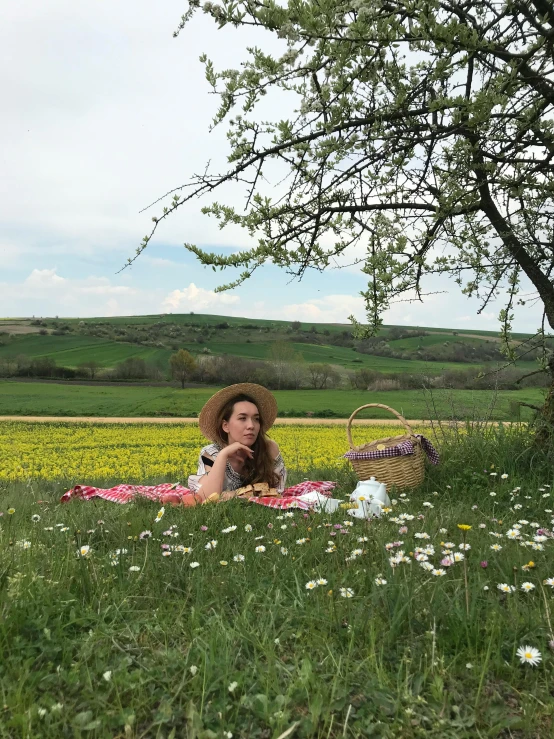 a woman laying in the grass with a straw hat