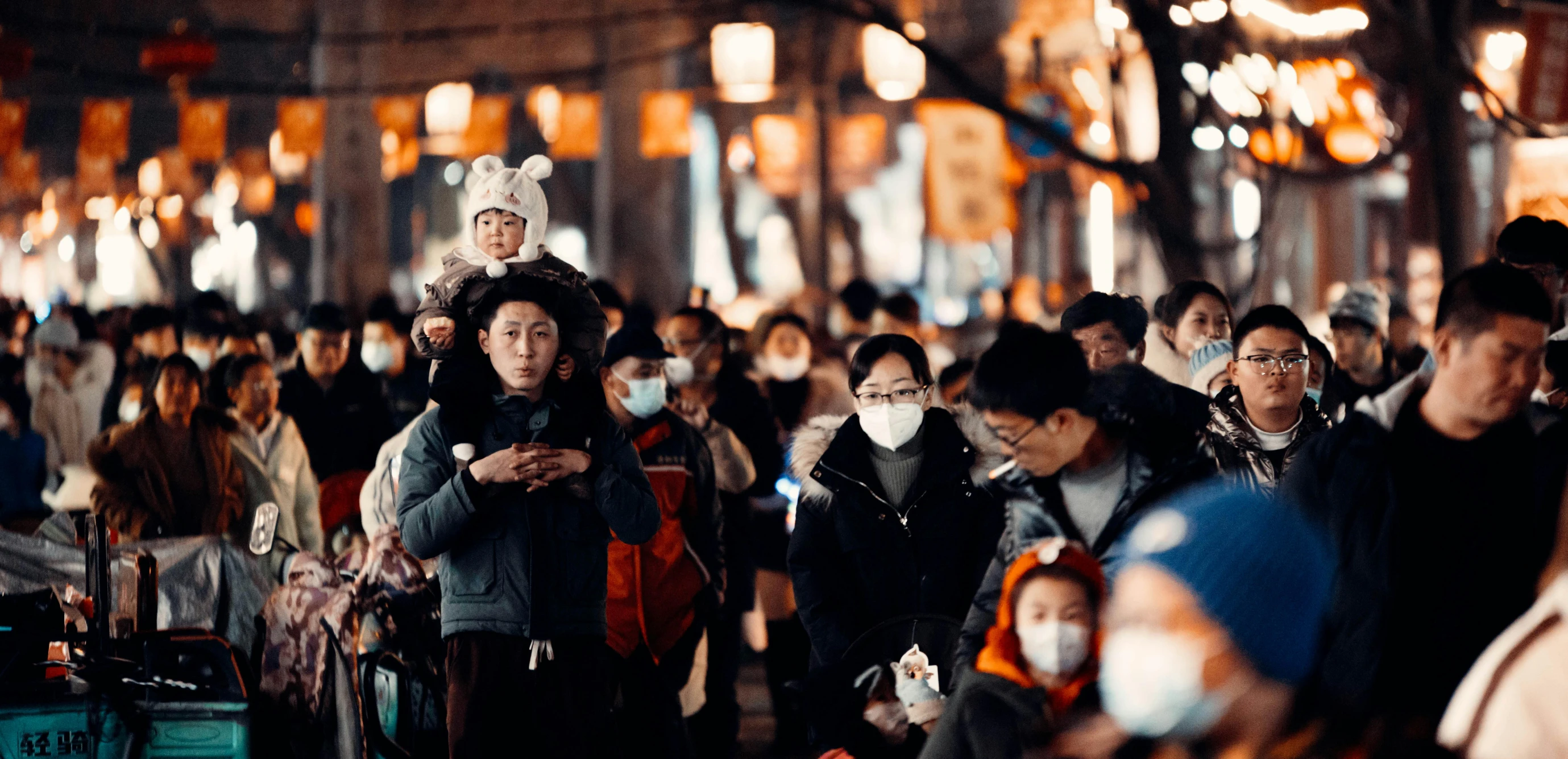 many people walking in a busy area with many lanterns