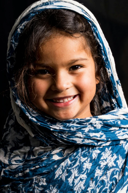 a  wearing blue and white shawl smiles for the camera