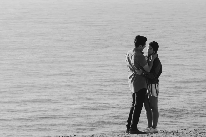 two people hug each other while standing on a beach