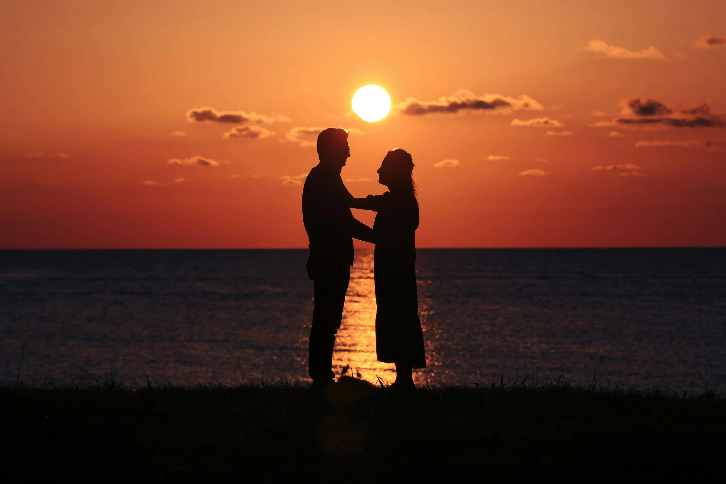 a couple standing near the ocean holding hands