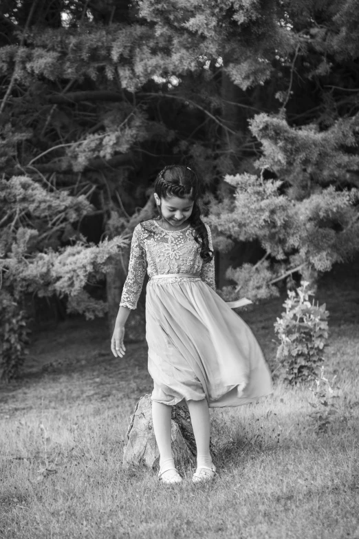 black and white po of girl in dress with ballerina shoes, playing