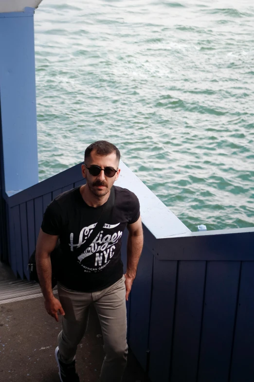 a man standing on a pier next to the ocean