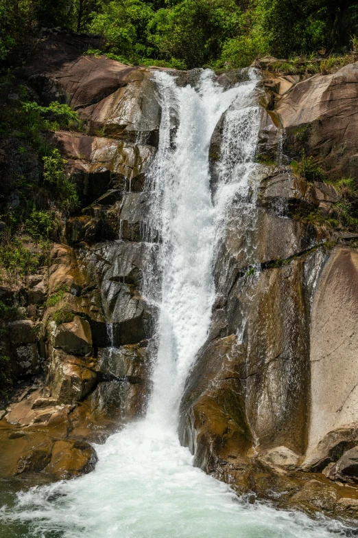 a waterfall is near some rocks in the water