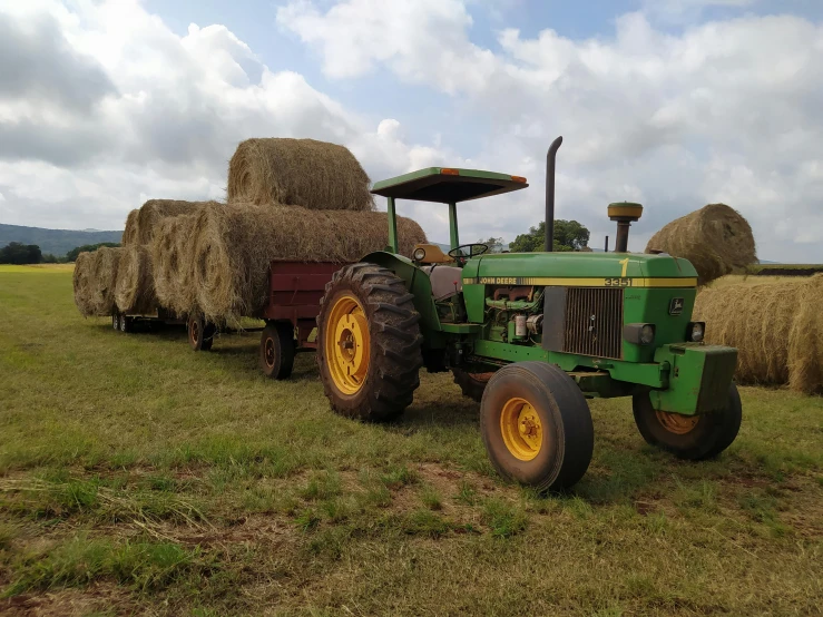 green tractor with bales in front of it