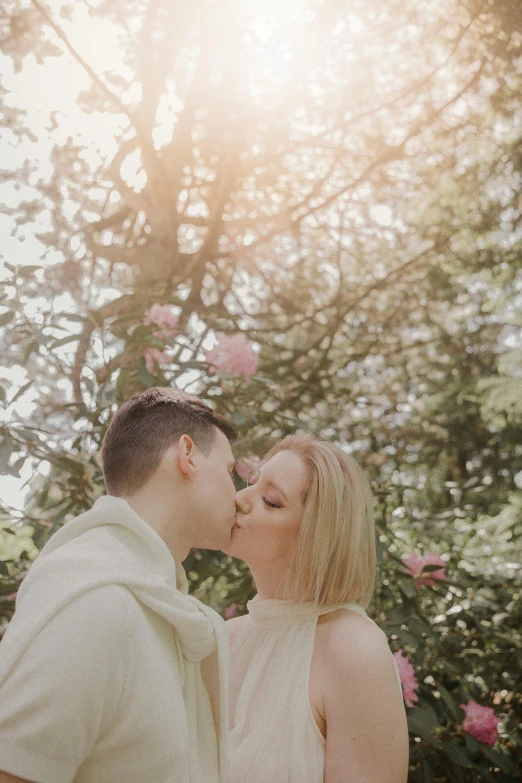 two people share a kiss under a tree