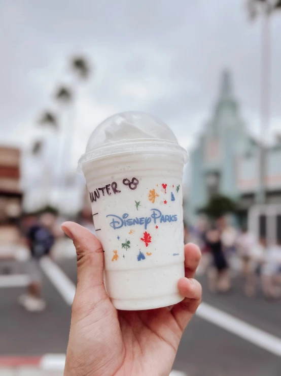 the hand is holding a plastic cup with writing on it