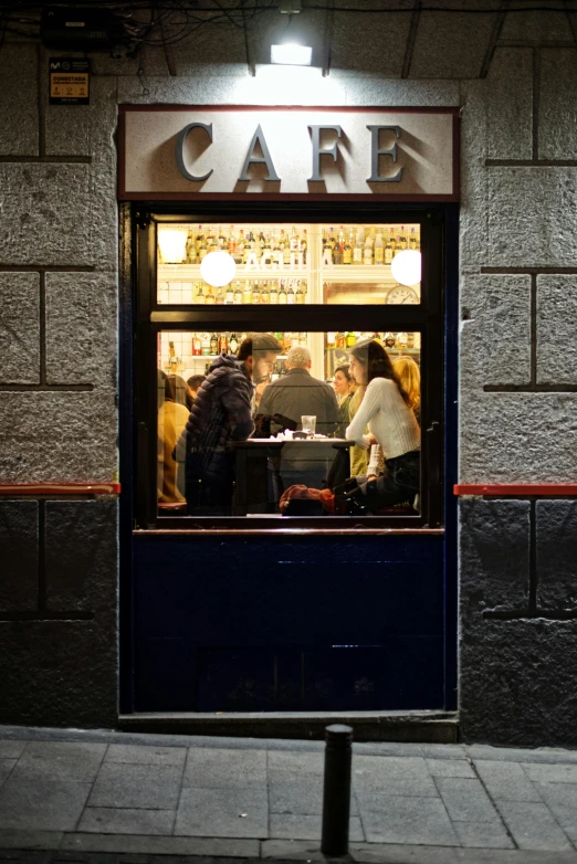 people sitting in the window of a cafe at night