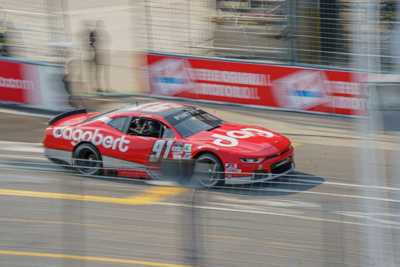 a red race car that is driving down a road