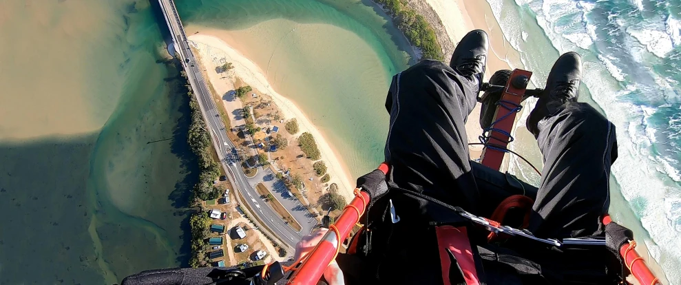 a man in a parachute on the water's edge