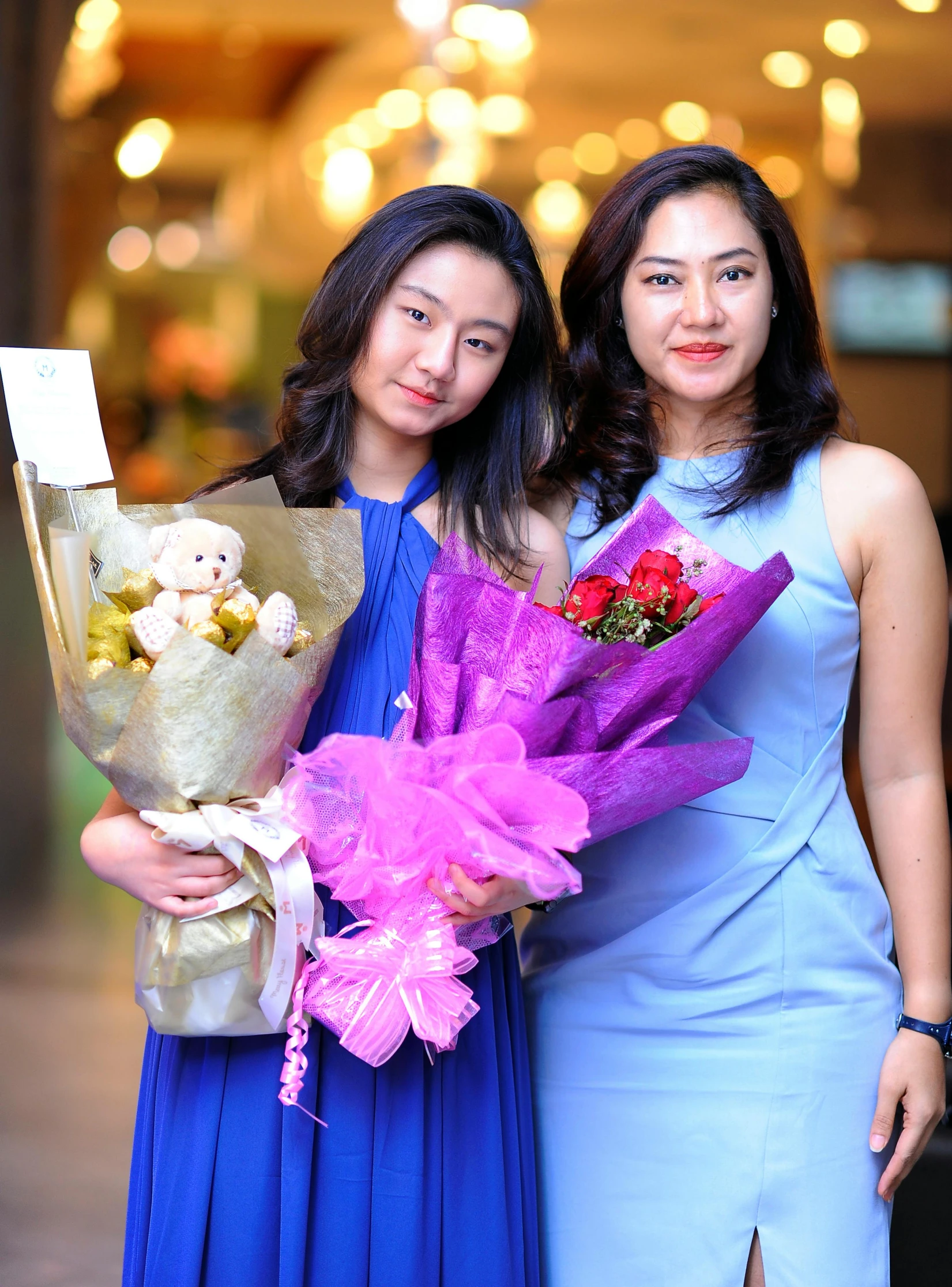 two woman standing next to each other holding flowers