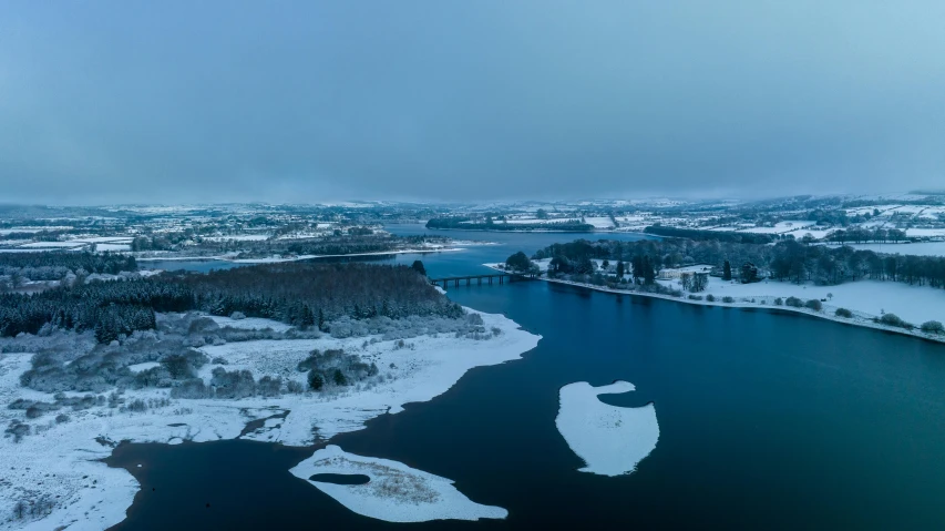 a lake with water surrounded by snow covered ground