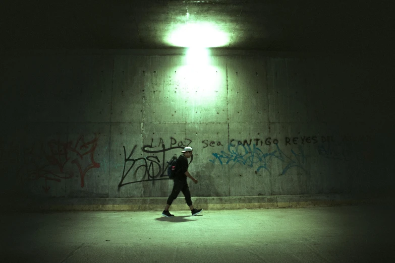 a man walking by the side of a wall in dark