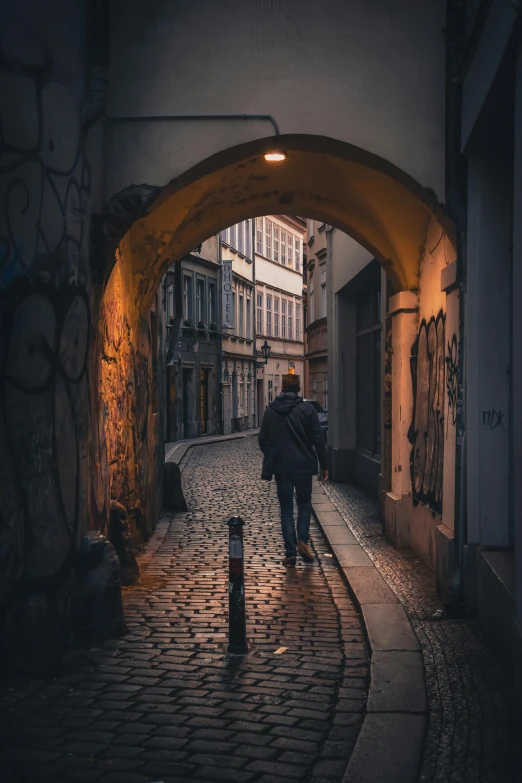 two people walk in the street under an arch