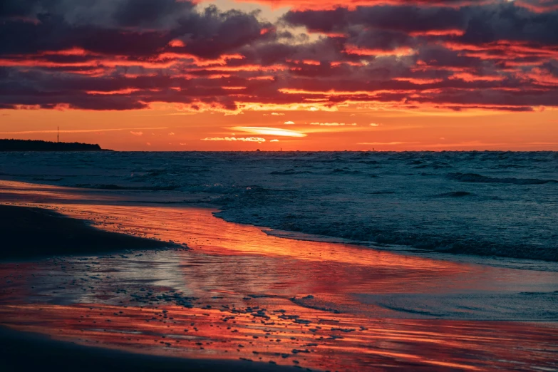 the setting sun shining in the sky over the beach