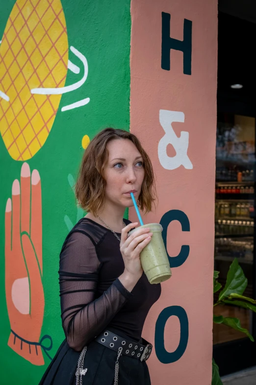 a woman is holding a beverage up to her face