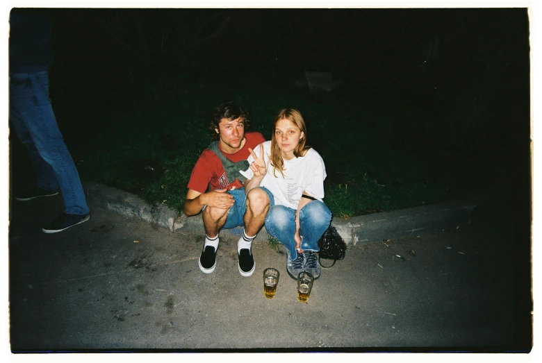 young man and woman sitting on skateboard at night