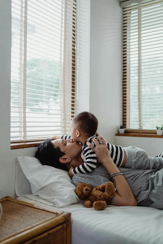 a woman in pajamas laying on a bed holding a stuffed animal