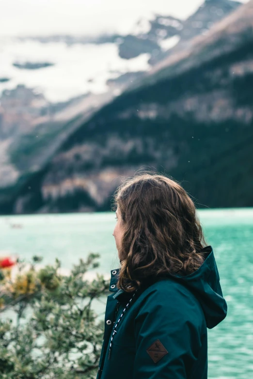 a girl staring out over a mountain lake