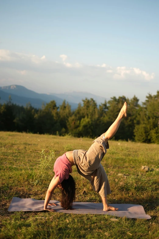 a woman practices yoga in the middle of a field