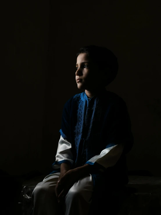 a man in a blue shirt sitting in the dark