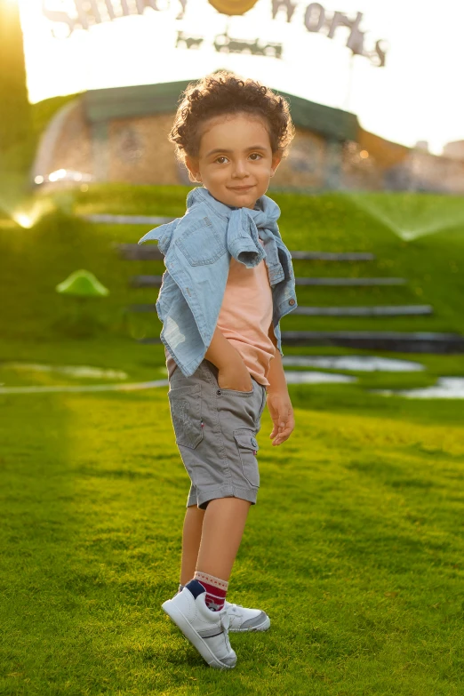 a little boy in shorts is standing on the grass