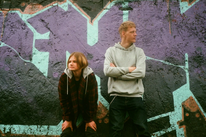 man and woman standing in front of purple graffiti