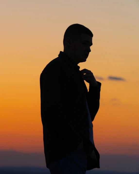 the man is standing in front of the setting sun