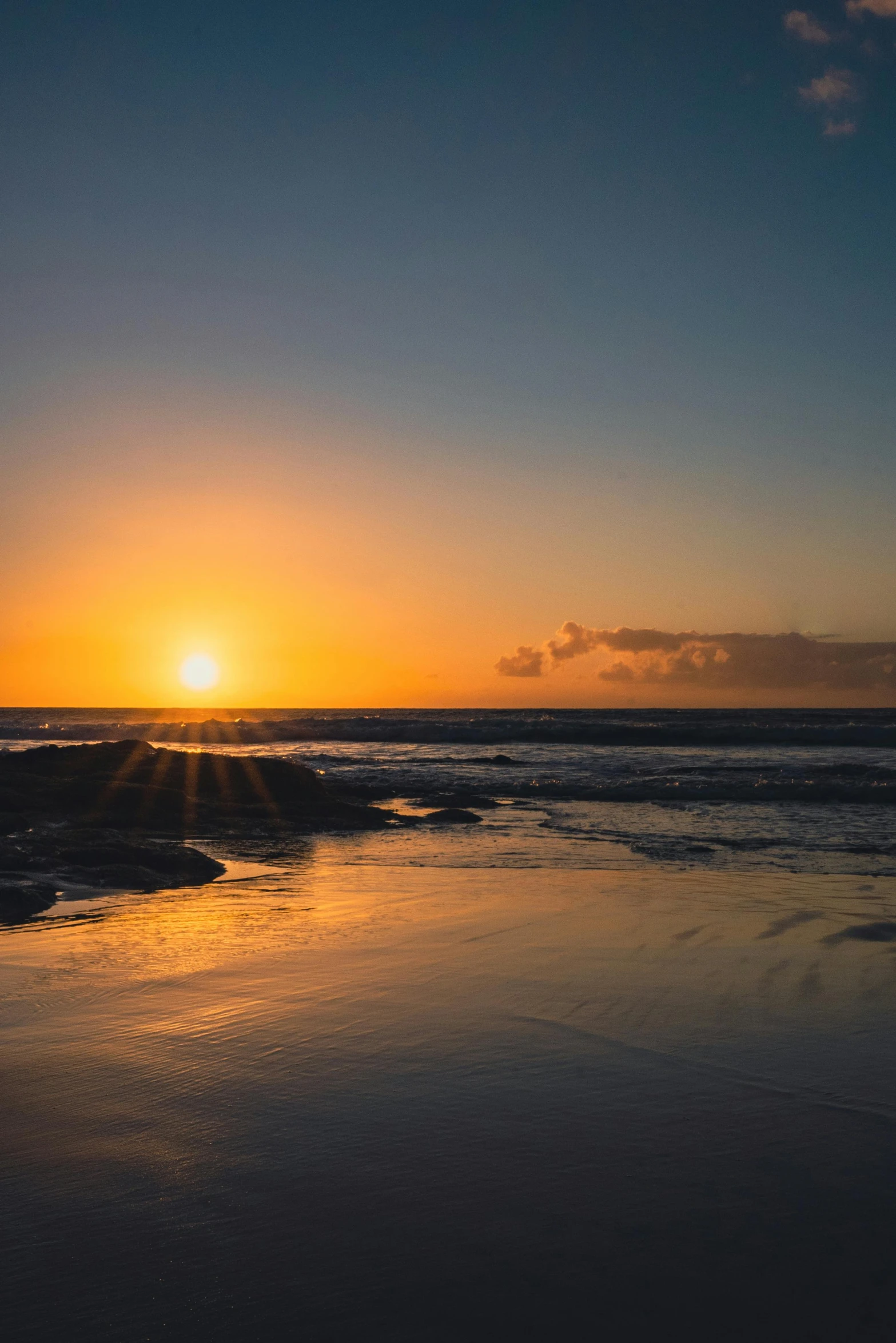 the sun rises behind a wave on the beach