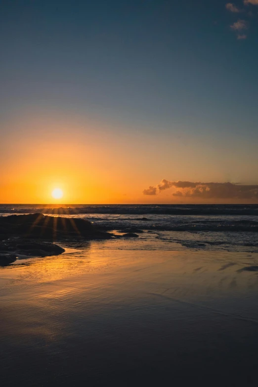 the sun rises behind a wave on the beach