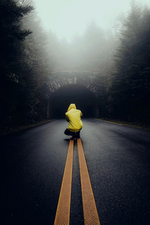 a person in yellow sitting on the side of the road