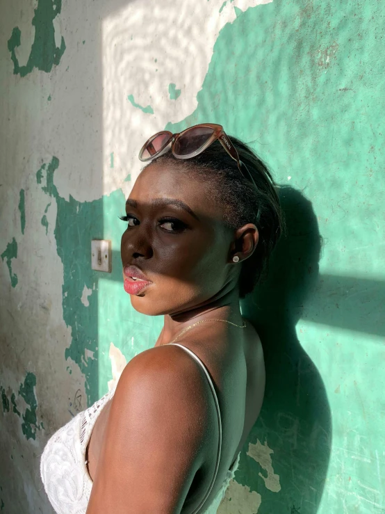 a woman with make up and large dark sunglasses stands in front of a wall